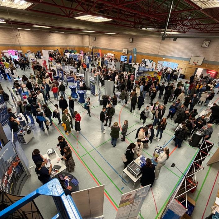 Blick über die mit Ausstellungsständen bestückte Turnhalle mit vielen Menschen (c) Marc Schmitt Blick über die mit Ausstellungsständen bestückte Turnhalle mit vielen Menschen